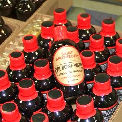 A Box of 24 bottles of Evil Bone Water with red Tops one bottle is lifted up